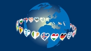 Die Länder-Fähnchen-Herzen der Eurovisionslogi laufen um eine Weltkugel.  Foto: Jonas Ockelmann