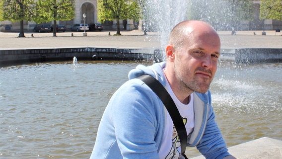 Der britische Illustrator Ben Morris sitzt vor einem Brunnen in Kopenhagen © Ben Morris 
