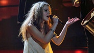 Die dänische Sängerin Emmelie de Forest singt sitzend auf einer Bühne. © EBU Foto: Wouter van Vliet