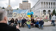 Menschen sitzen vor dem großen Eurovision-Schriftzug am Maidan-Platz in Kiew. © picture alliance / Julian Stratenschulte/ dpa Foto: Julian Stratenschulte