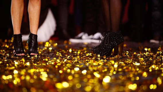 Die Waden und schwarzen Schuhe von Sängerin Ann Sophie, die auf der mit goldenem Konfetti bedeckten Bühne des deutschen ESC-Vorentscheids steht. © NDR Foto: Rolf Klatt