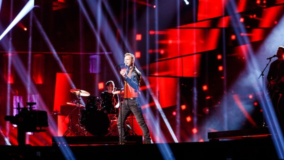 Nicky Byrne steht in einer roten Lederjacke, die Bühne ist rot ausgeleuchtet. © eurovision.tv Foto: Thomas Hanses (EBU)