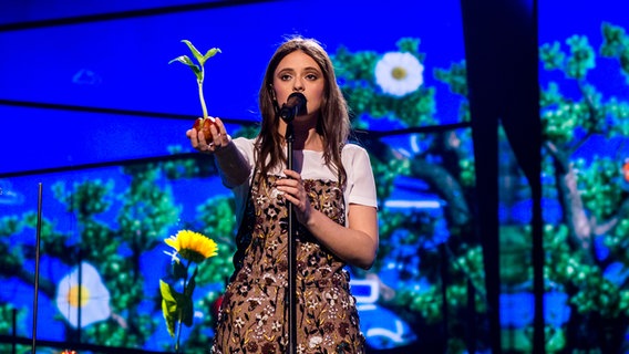 Francesca steht am Mikrophon und hält eine Pflanze in der Hand. © eurovision.tv Foto: Anna Velikova (EBU)