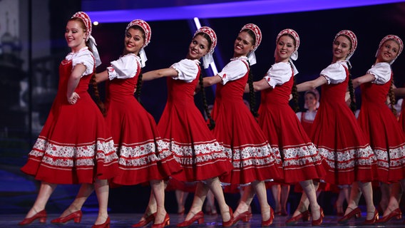 Ein Gruppe von Tänzerinnen in roter Tracht tanzt über die Bühne. © eurovision.tv Foto: Indrek Galetin (EBU)