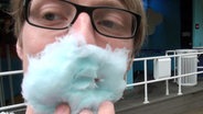 Lukas Heinser hält sich einen Bart aus Zuckerwatte ins Gesicht. © NDR 