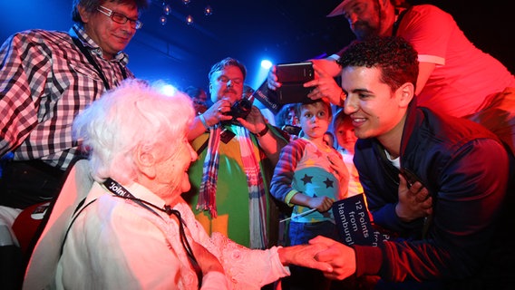 Die 104-Jährige Ella gibt dem Sänger Basim bei einem Auftritt die Hand © NDR Foto: Rolf Klatt