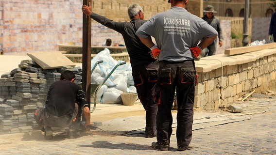 Drei Männer auf einer Baustelle in Baku  Foto: Julian Rausche