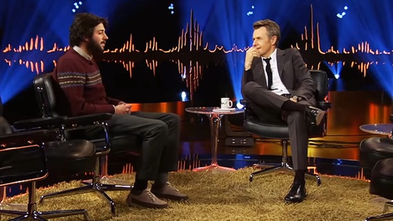 Der ehemalige ESC-Teilnehmer Salvador Sobral sitzt in einer Talkshow neben Moderator Fredrik Skavlans. © youtube.com/skavlan 