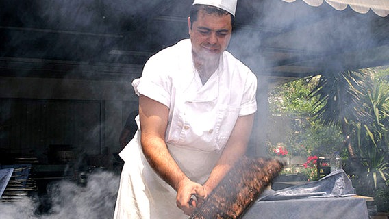 Am Grill schwenkt der Koch die Spare Ribs © NDR Foto: Rolf Klatt