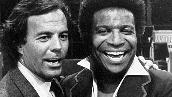 Gastgeber und Schlagersänger Roberto Blanco (r) mit dem spanischen Sänger Julio Iglesias, aufgenommen am 11.5.1982 während der Aufzeichnung der WDR-Fernsehshow "Ein Abend mit Roberto Blanco". © picture alliance Foto: Hans Dürrwald