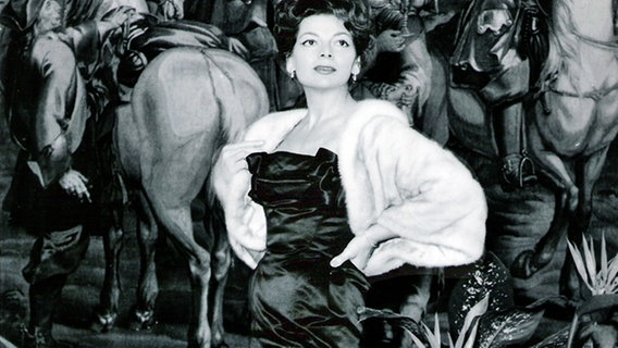 Lys Assia, Siegerin des 1. Grand Prix Eurovision im Jahr 1956, vor einem Gemälde.  