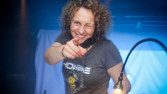 DJ Frau Hoppe zeigt in Richtung Kamera  