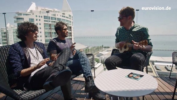 Ermal Meta, Fabrizio Moro und Stefan Spiegel sitzen auf einer Dachterasse in Lissabon. © NDR 