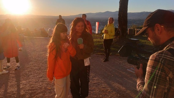 Fia und KiKA-LIVE-Moderatorin Sarah Parvanta im Sonnenuntergang auf dem Mont Gros in Nizza. Fia und KiKA-LIVE-Moderatorin Sarah Parvanta im Sonnenuntergang auf dem Mont Gros in Nizza. © NDR Foto: Marcel Stober
