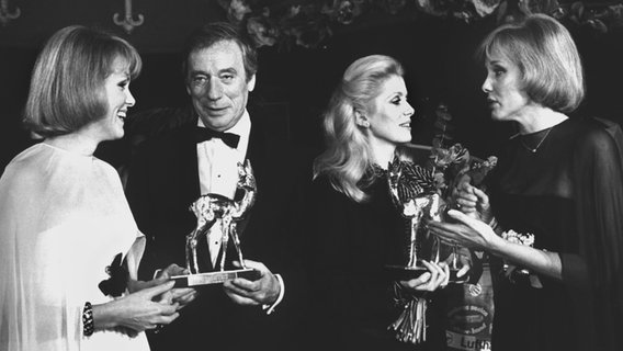 Alice und Ellen Kessler treffen Catherine Deneuve und Yves Montand 1976 bei der Bambiverleihung in München. © dpa - Bildarchiv Foto: Istvan Bajzat