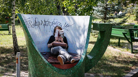 Eine Frau liest in einem Park in der ukrainischen Hauptstadt Kiew © dpa 