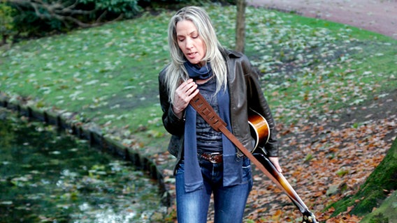 Die französische Sängerin Corinne Hermès mit Gitarre im Park. 1983 gewann sie für Luxemburg den Eurovision Song Contest mit dem Titel "La vie est cadeaux". © AWE Music Foto: Lola D