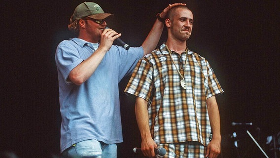 Stefan Raab legt im August 1996 Bürger Lars Dietrich (rechts) auf einer Bühne mit einer tröstenden Geste die Hand auf den Kopf. © imago/Horst Galuschka 