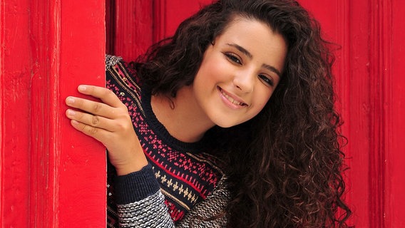 Die Junior Eurovision Song Contest Teilnehmerin Christina Magrin beugt sich aus einer roten Tür hervor © EBU Foto: NN