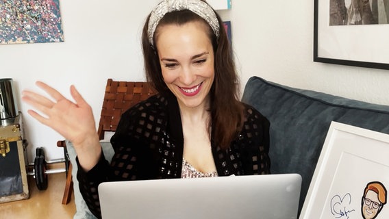 Alina Stiegler sitzt fröhlich winkend vor einem Laptop.  Foto: Screenshot