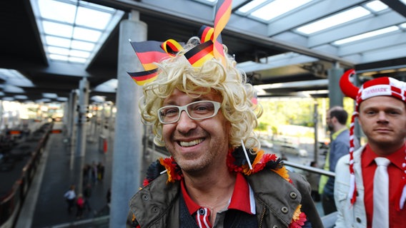 Ein ESC-Fan mit einer Perücke, darin sind Deutschlandfähnchen gesteckt. © NDR Foto:  Andrej Isakovic