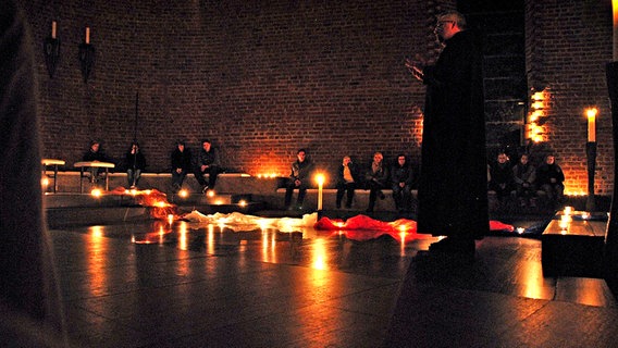 Ein Mönch spricht vor mehreren Jugendlichen bei Kerzenlicht in einem großen Raum © Abtei Königsmünster 