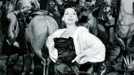 Lys Assia, Siegerin des 1. Grand Prix Eurovision im Jahr 1956, vor einem Gemälde.  