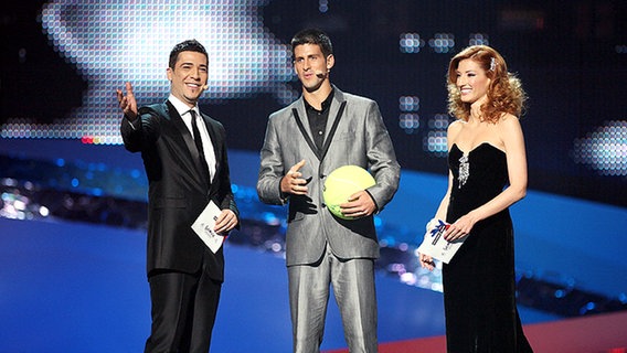 Zeljko Joksimovic und Jovana Jankovic begrüßen den Tennisspieler Novak Djokovic auf der Bühne im ersten Halbfinale © NDR Foto: Rolf Klatt