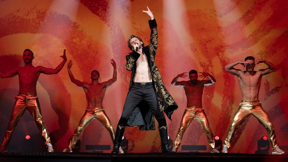 Dan Stevens als russischer Kandidat Alexander Lemtov zusammen mit vier halbnackten Tänzern im Netflix-ESC-Film. Dan Stevens als russischer Kandidat Alexander Lemtov zusammen mit vier halbnackten Tänzern im Netflix-ESC-Film. Foto: John Wilson/NETFLIX