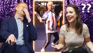 Ein lachender Stefan Spiegel und eine ratlose Alina Stiegler neben dem tanzenden deutschen ESC-Act Jendrik. © NDR 