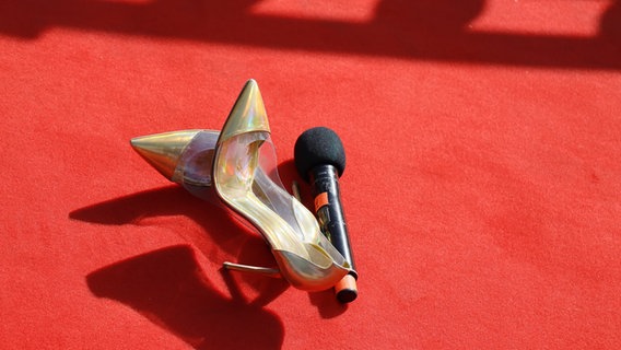 Ein paar Schuhe und ein Mikrophon liegen dem roten Teppich bei der Eröffnungszeremonie zum ESC in Kiew. © Eurovision.tv Foto: Andres Putting