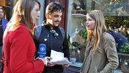 Videoreporterin Sandra Hofmann (links) in Amsterdam mit dem Eurovisionsfan Yilmaz Metin und der Schweizer ESC-Kandidatin Anna Rossinelli © NDR Foto: Patricia Batlle