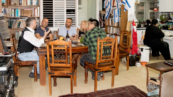 Menschen sitzen am Tisch und unterhalten sich bei einem Essen.  Foto: Claudia Timmann