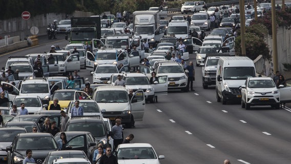 Menschen in Tel Aviv stehen auf der Autobahn neben ihren Autos. Sie gedenken den gefallenen Soldaten während einer Sirene. © dpa Foto: Ilia Yefimovich