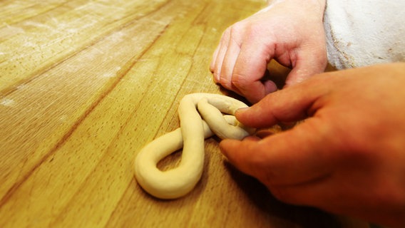 Ein Bäcker formt einen Violinschlüssel aus Hefeteig. © NDR Foto: Rolf Klatt