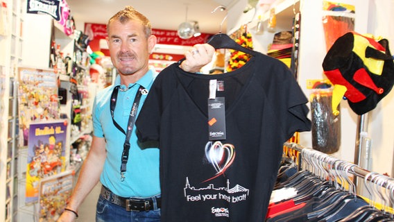 Souvenir-Shop Betreiber Werner Stamme präsentiert seine T-Shirt Auswahl. © NDR Foto: Rolf Klatt