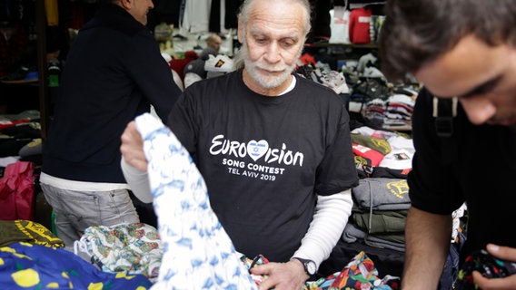 Ein Verkäufer mit Eurovision-T-Shirt sortiert seine Ware  