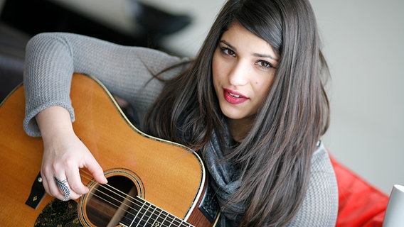 Yana spielt im Hotelzimmer auf ihrer Gitarre.  