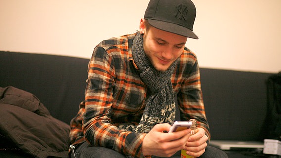 Roman mit seinem Handy im Backstage-Bereich von "Unser Star für Baku". © NDR Foto: Claudia Timmann