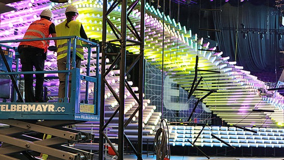 Arbeiter vor der aus beleuchteten Stehlen bestehenden Bühne in der Wiener Stadthalle © ORF.at/ Thomas Hangweyrer 