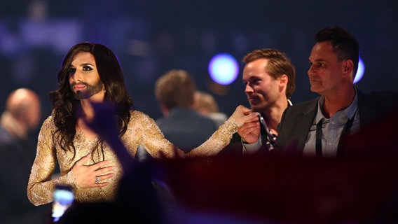 Die Sängerin Conchita Wurst hält einem Delegationsmitglied der österreichischen ESC-Delegation die Hand im Greenroom in Kopenhagen © NDR Foto: Rolf Klatt