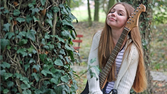 Die Junior Eurovision Song Contest Teilnehmerin Olivia Wieczorek posiert mit einer E-Gitarre zwischen Bäumen © EBU Foto: TVP