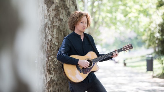 Portugal, Lissabon: Der deutsche ESC-Teilnehmer Michael Schulte steht mit einer Gitarre an einem Baum. © dpa-Bildfunk Foto: Jörg Carstensen