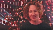 Michael Schulte steht vor einem geschmückten Weihnachtsbaum.  