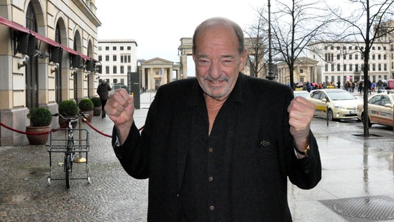 Ralph Siegel steht vor dem Brandenburger Tor in Berlin und drückt die Daumen. © NDR/Nicole Janke Foto: Nicole Janke