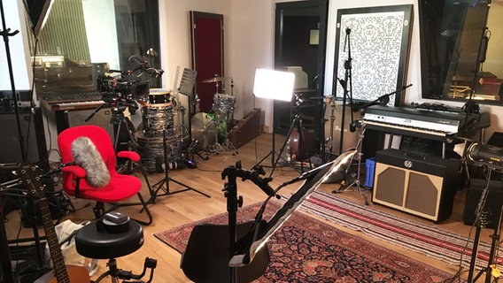 Raum in einem Musikstudio mit Keyboards, Gitarren, Schlagzeug, Mikrofonen, Notenständern und einem roten Stuhl  Foto: Marcel Stober