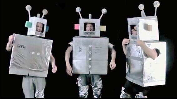Drei Bandmitglieder von Sie kamen Australien stehen nebeneinander in Roboter-Kostümen. © Sie kamen Australien 