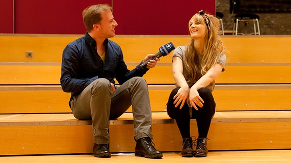 Die Musikerin Betty Dittrich (r.) und eurovision.de Reporter Sascha Sommer sitzen auf einer Treppe. © NDR Foto: Claudia Timmann