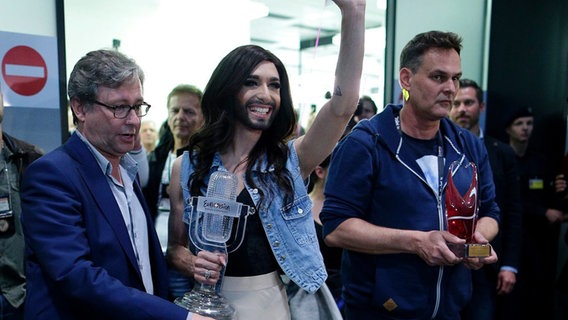 Conchita Wurst winkt bei ihrer Ankunft am Flughafen Wien der Presse zu. © dpa / Georg Hochmuth Foto: Georg Hochmuth