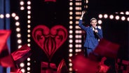 Jüri Pootsmann aus Estland hält die Hand singend hoch, im Hintergrund leuchtet ein rotes Herz auf der Bühne © NDR Foto: Rolf Klatt